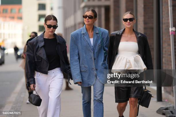 Annabel Rosendahl wears black sunglasses, a black body, a black shiny leather jacket, white wide legs pants, a black shiny leather handbag, Darja...