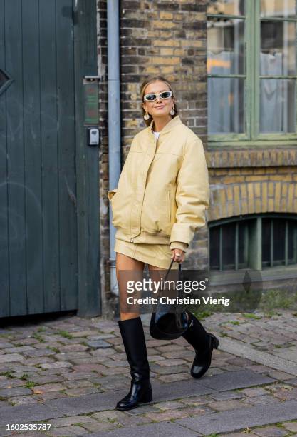 Zoë Pastelle wears yellow jacket, skirt, black bag, boots outside Remain during the Copenhagen Fashion Week Spring/Summer 2024 on August 08, 2023 in...