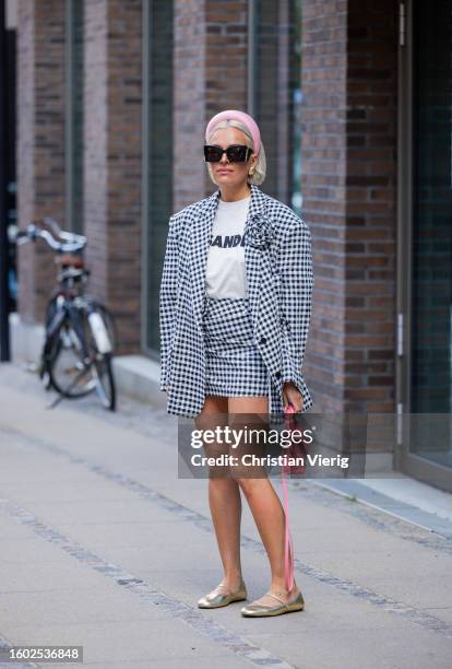 Guest wears black white checkered blazer, skirt outside Lovechild during the Copenhagen Fashion Week Spring/Summer 2024 on August 08, 2023 in...