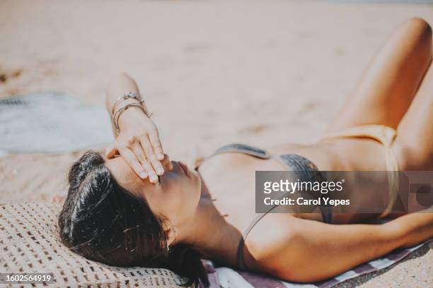 beautiful woman sun bathing during holidays at the beach - arm sun beach stock-fotos und bilder