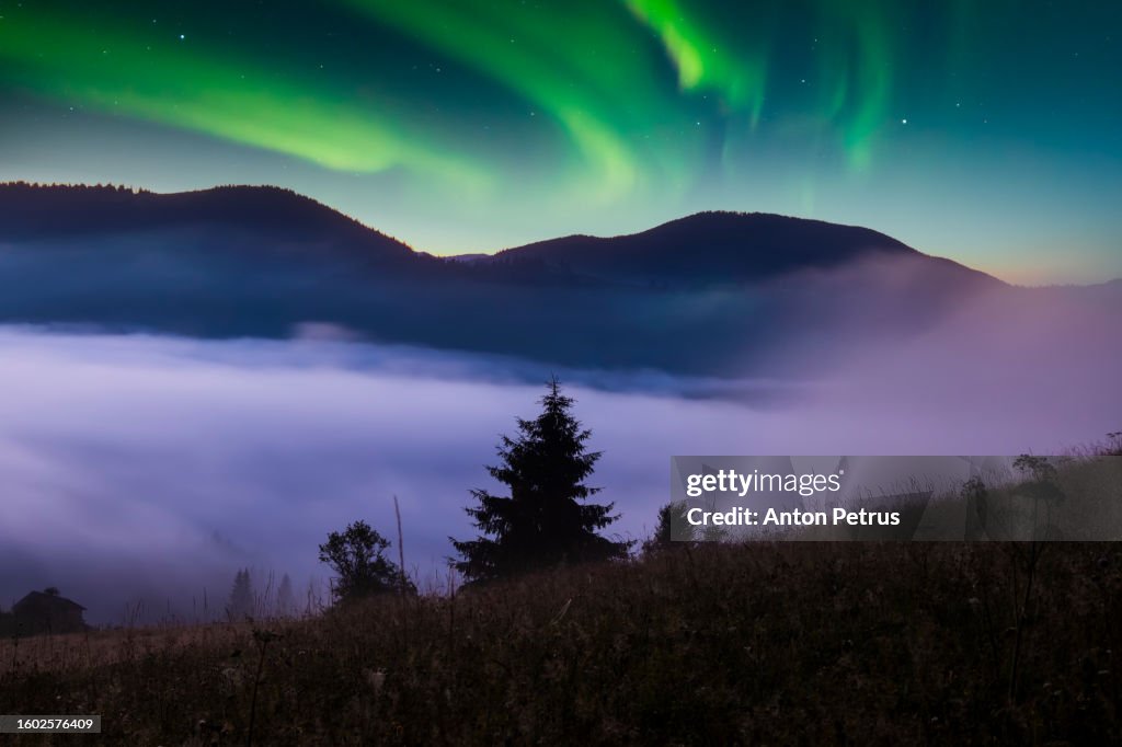 Fog in mountains at night with northern lights