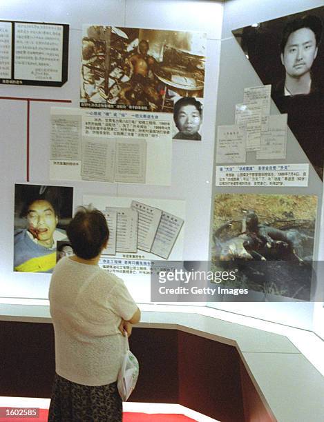 Chinese woman looks at a display of images organisers describe as showing deceased members of the Falun Gong sect in an anti-cult exhibition July 19,...