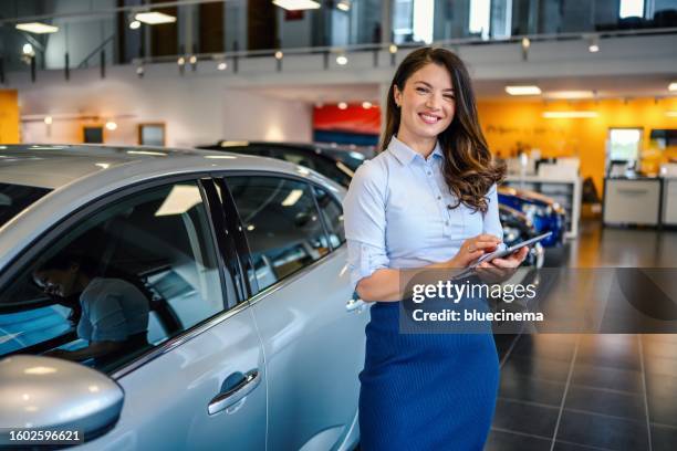 ritratto di una bella commessa di auto femminile che lavora nello showroom - venditore di automobili foto e immagini stock