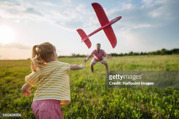 playful father and daughter throwing styrofoam glider planes. - gleiten stock-fotos und bilder