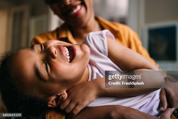 a happy cute little latin girl keeping her eyes closed while having fun with her unrecognizable nanny - nanny smiling stockfoto's en -beelden