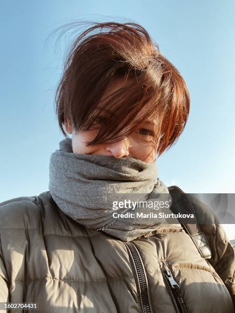 selfie outdoor portrait of a stylish woman in jacket and scarf in cool sunny day. - looking at camera stockfoto's en -beelden