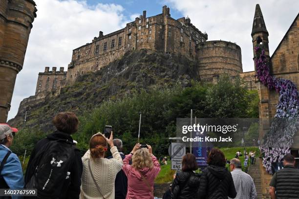 Festivalgoers and tourists photograph Edinburgh Castle from the Grassmarket during the Edinburgh Festival Fringe, on August 16, 2023 in Edinburgh,...