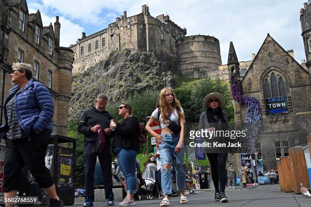 Festivalgoers and tourists stroll in the city's Grassmarket during the Edinburgh Festival Fringe, with Edinburgh Castle dominating the background, on...
