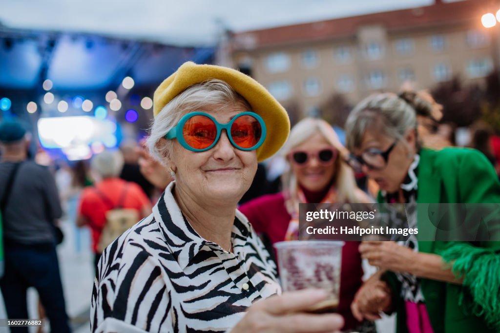 Happy three senior friends having fun at outdoor concert.