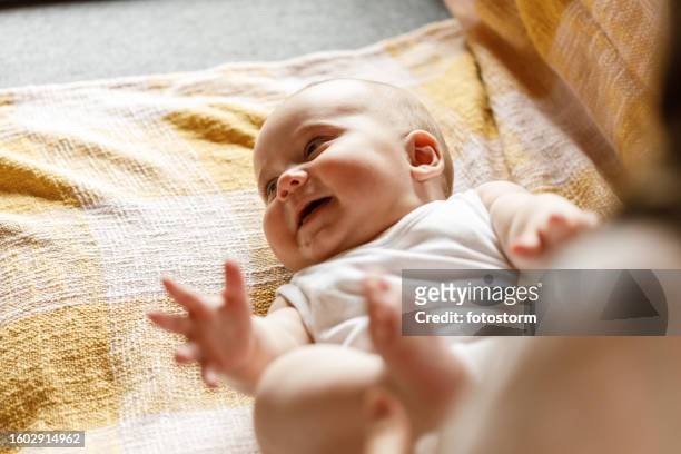 baby boy playing with his feet and legs while having his diaper changed - nappy change stockfoto's en -beelden