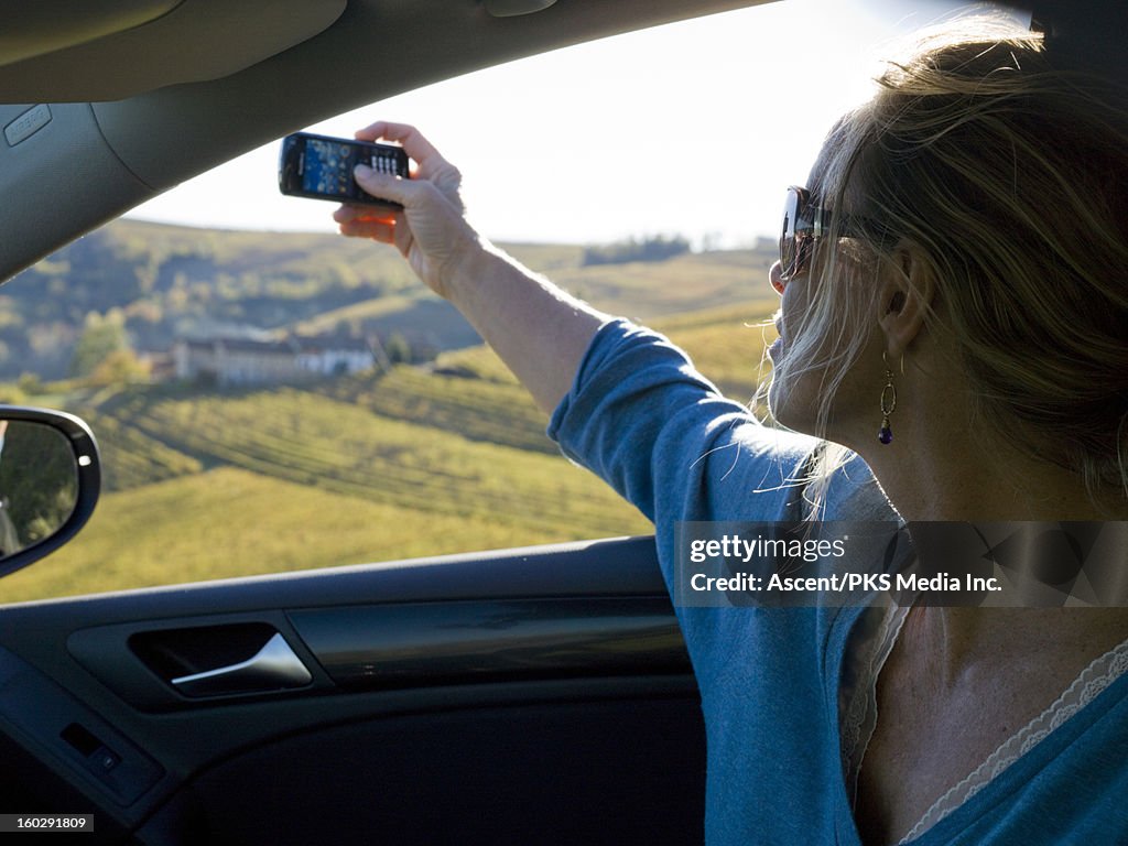 Woman takes picture form car, above vineyards