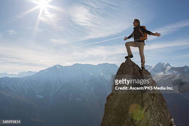 hiker stands on pinnacle summit, arms outstretched - celebrates firsts imagens e fotografias de stock
