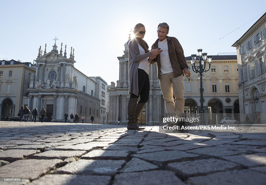 Couple pause to look at text message, piazza