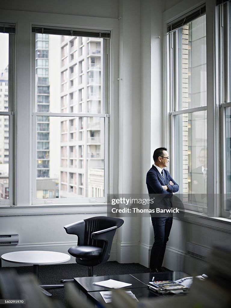 Smiling businessman looking out office window