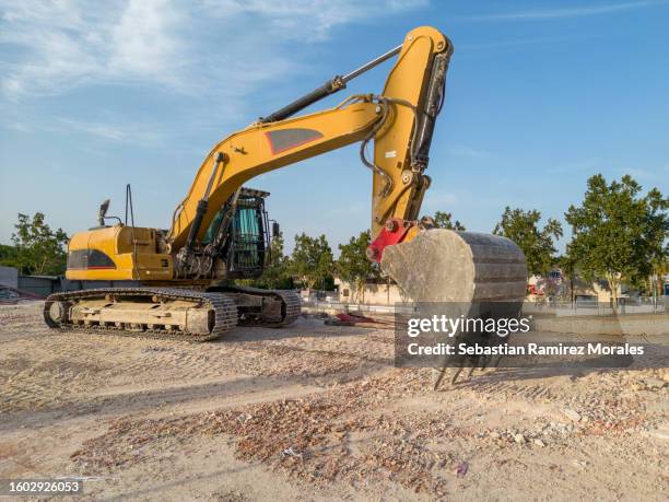 yellow excavator at construction site - grondverzetmachine stockfoto's en -beelden