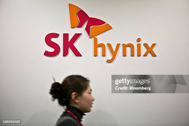 An SK Hynix Inc. Employee walks past the company's logo displayed at its headquarters in Seoul, South Korea, on Monday, Jan. 28, 2013. Hynix is...