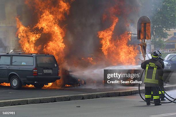 Firemen attempt to put out cars set on fire by anti-G8 protesters July 20, 2001 in central Genoa. Approximately 600 violent protesters fought with...