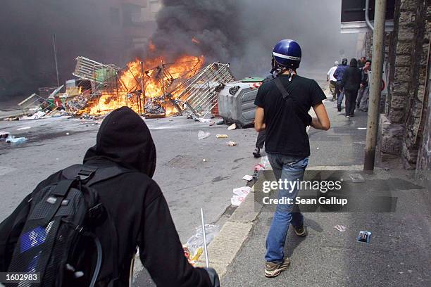 Anti-G8 protesters make their way past a barricade they set alite July 20, 2001 in central Genoa. Approximately 600 violent protesters fought with...