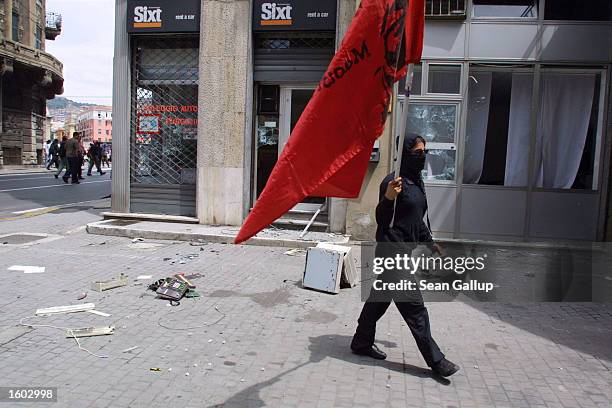 An anti-G8 protester passes a smashed car rental store July 20, 2001 in central Genoa. Approximately 600 violent protesters fought with police,...