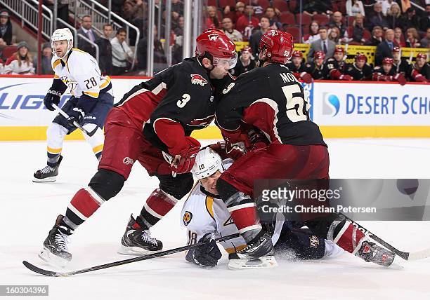 Brandon Yip of the Nashville Predators is checked by Keith Yandle and Derek Morris of the Phoenix Coyotes during the NHL game at Jobing.com Arena on...