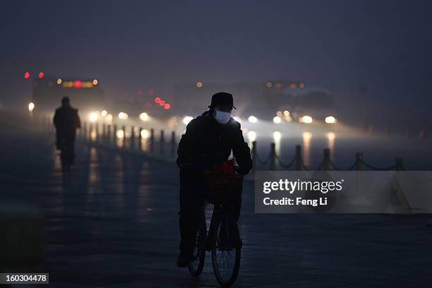 Men wearing the mask rides a bicycle on the street during severe pollution on January 29, 2013 in Beijing, China. The 4th dense fog envelops Beijing...