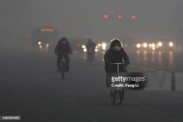 Beijing residents wearing the mask ride amid fog during severe pollution on January 29, 2013 in Beijing, China. The 4th dense fog envelops Beijing...