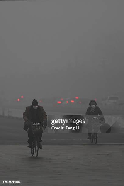 Beijing residents wearing the mask ride amid fog during severe pollution on January 29, 2013 in Beijing, China. The 4th dense fog envelops Beijing...