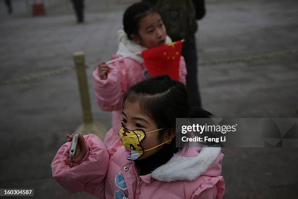 Little girl wears the cartoon mask at the Tiananmen Square during severe pollution on January 29, 2013 in Beijing, China. The 4th dense fog envelops...