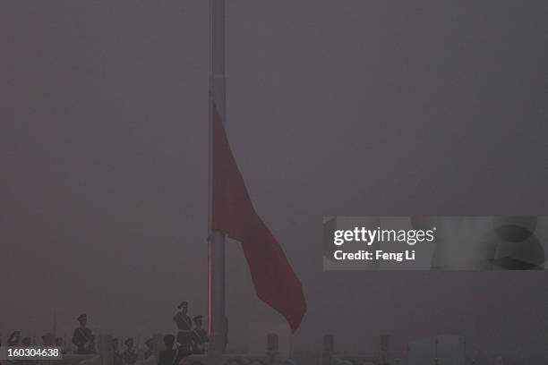 Chinese paramilitary police officers salute during the flag-raising ceremony with severe pollution at Tiananmen Square on January 29, 2013 in...