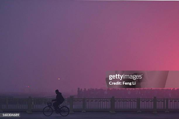 Men rides a bicycle as tourists waiting the flag-raising ceremony during severe pollution at Tiananmen Square on January 29, 2013 in Beijing, China....