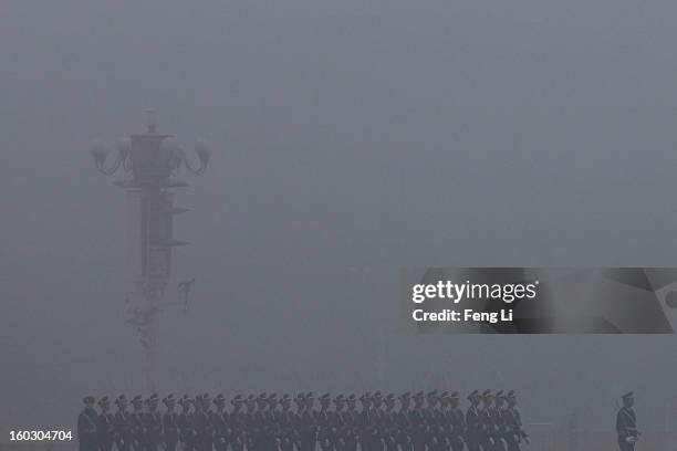 Chinese paramilitary police officers march during the flag-raising ceremony with severe pollution at Tiananmen Square on January 29, 2013 in Beijing,...