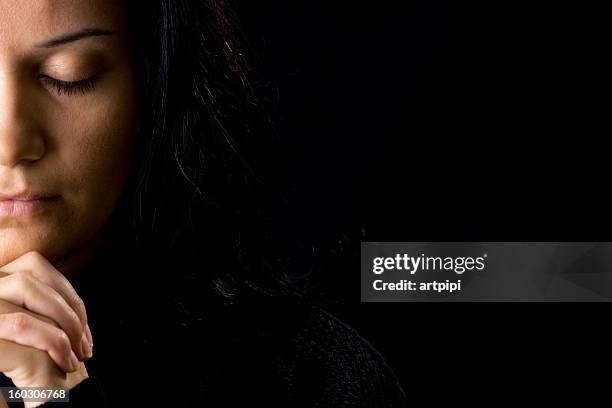 a woman deep in prayer and a black background - kristendom bildbanksfoton och bilder