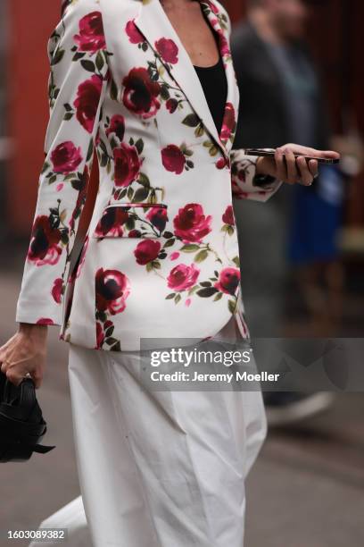 Guest is seen wearing black cotton tank top, white with red roses print pattern blazer jacket, white wide leg suit pants, black leather handbag,...