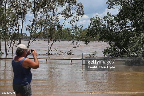 Locals watch the Burnett River rises as parts of southern Queensland experiences record flooding in the wake of Tropical Cyclone Oswald on January...