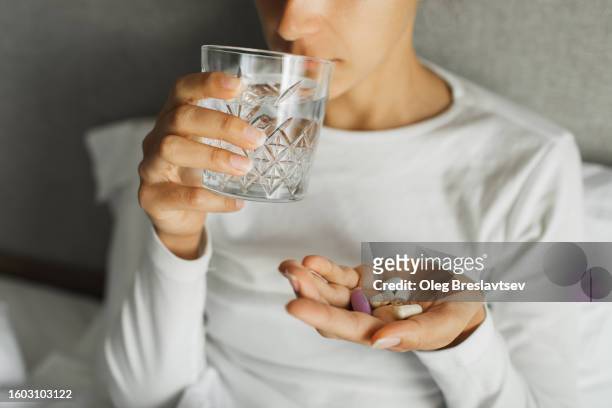 woman takes daily vitamins with water. nutritional supplement for female health - nutritional supplement stockfoto's en -beelden