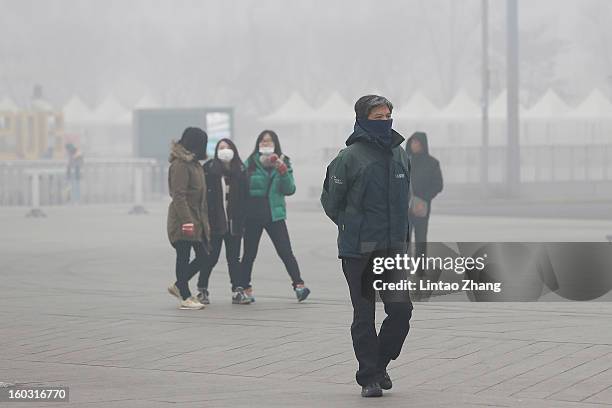 Beijing residents wearing masks walk through fog as severe pollution continues to affect the capital on January 29, 2013 in Beijing, China. China's...