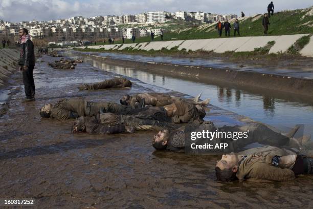 Graphic content / TOPSHOT - GRAPHIC CONTENT A Syrian man stands next to the bodies of executed men on the side of a canal in the northern Syrian city...