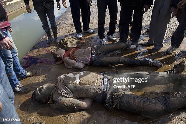 Young Syrians look at the bodies of executed men after being dragged from the water onto the side of a canal in the northern city of Aleppo on...