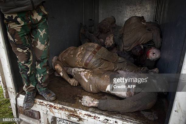 Syrian rebel stands next to the bodies of executed men being piled up in the back of a lorry in the northern city of Aleppo before transporting the...