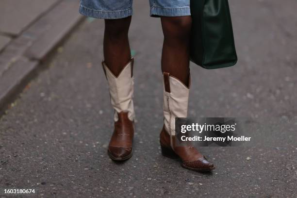 Guest wears Tom Ford blue denim shorts, dark green leather bag, brown / white cowboy boots, outside Sunflower, during the Copenhagen Fashion Week...