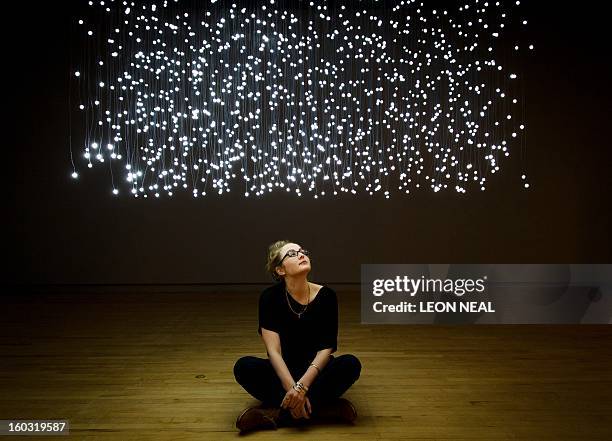 Journalist sits beneath a work entitled "Exploded View " by Jim Campbell at the "Light Show" exhibition at the Hayward Gallery in central London on...