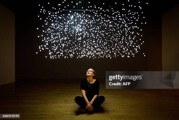 Journalist sits beneath a work entitled "Exploded View " by Jim Campbell at the "Light Show" exhibition at the Hayward Gallery in central London on...
