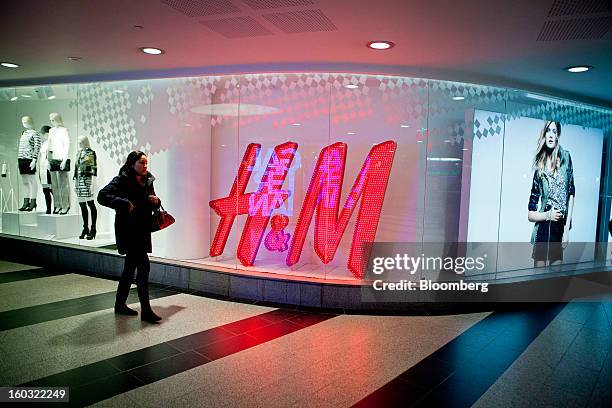 Pedestrian passes an illuminated logo in the window of a Hennes & Mauritz AB store in Stockholm, Sweden, on Tuesday, Jan. 29, 2013. Hennes & Mauritz...