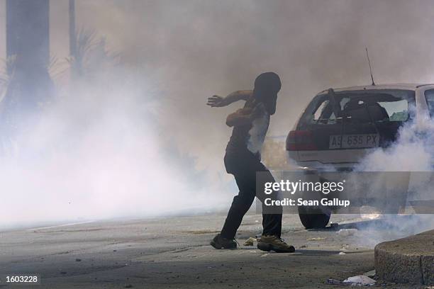 An anti-G8 protester throws a tear gas canister back at police through a fog of tear gas July 21, 2001 in Genoa, Italy. Several thousand violent...