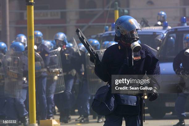 Riot policeman with a tear gas launcher and other officers advance toward anti-G8 protesters July 21, 2001 in Genoa, Italy. Several thousand violent...