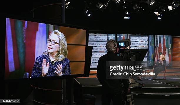 Secretary of State Hillary Clinton appears on a television screen in the studo as she answers questions from youths from around the world during a...