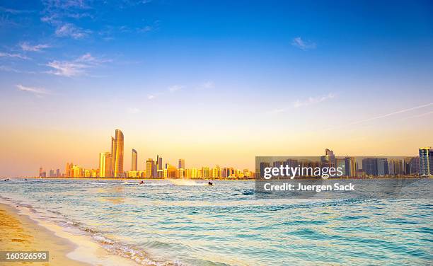 beach with backdrop of abu dhabi skyline at sunset - abu dhabi skyline stock pictures, royalty-free photos & images