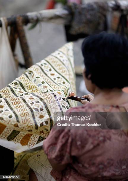 One of the women employees working on her design is pictured here at the Danar Hadi batik production company, where the monthly wage is around 90...