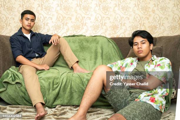 teenage boys sitting on a sofa - chino stock pictures, royalty-free photos & images