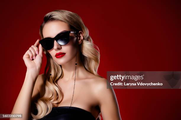 portrait of luxury woman touch sunglass criminal gang leader authority over maroon bright color background - maroon hair stock pictures, royalty-free photos & images